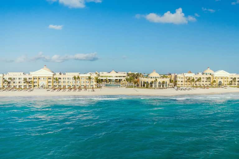 Beachfront resort with cream and yellow buildings featuring domed roofs along sandy beach and turquoise ocean