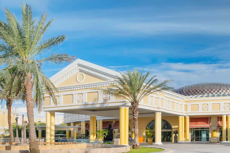 Yellow columned hotel entrance with classical architecture and palm trees