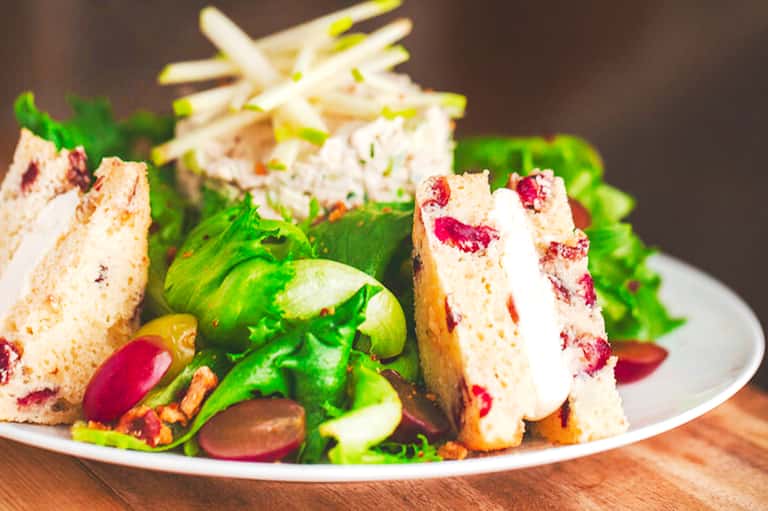Gourmet sandwich with colorful vegetables and garnishes on a white plate