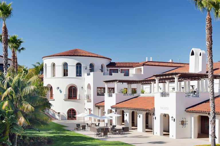 Spanish colonial-style resort building with white walls, arched windows, and palm trees