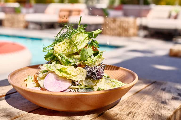 Gourmet salad served poolside at resort restaurant with pool in background