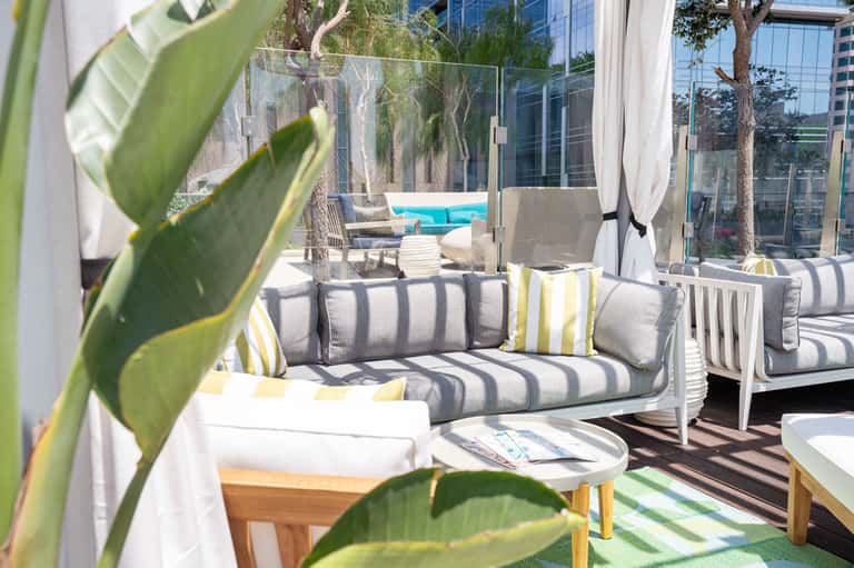 Modern rooftop terrace with striped furniture, pool view, glass railings, and urban backdrop