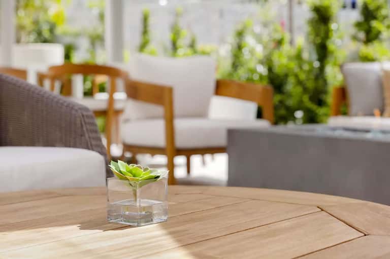Modern outdoor lounge area with wooden furniture, potted plants, and minimalist decor