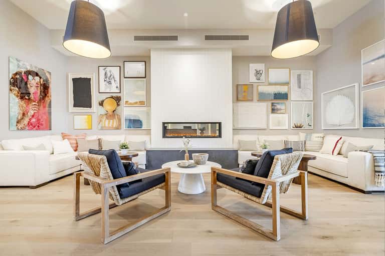 Contemporary living room with white sofas, fireplace, gallery wall art, and wooden accent chairs