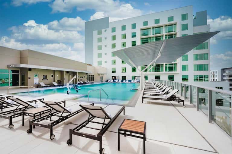 Contemporary resort pool deck with modern architecture, lounge chairs, and turquoise water