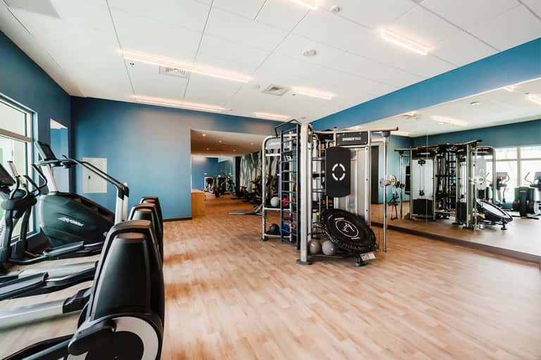 Fitness center with cardio equipment, blue accent walls, and wooden flooring