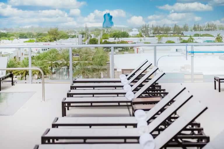 Rooftop lounge chairs overlooking theme park with blue guitar-shaped structure in distance