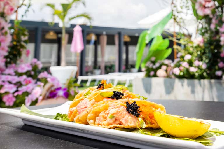 Salmon tartare with caviar and microgreens on outdoor terrace with pink flowers
