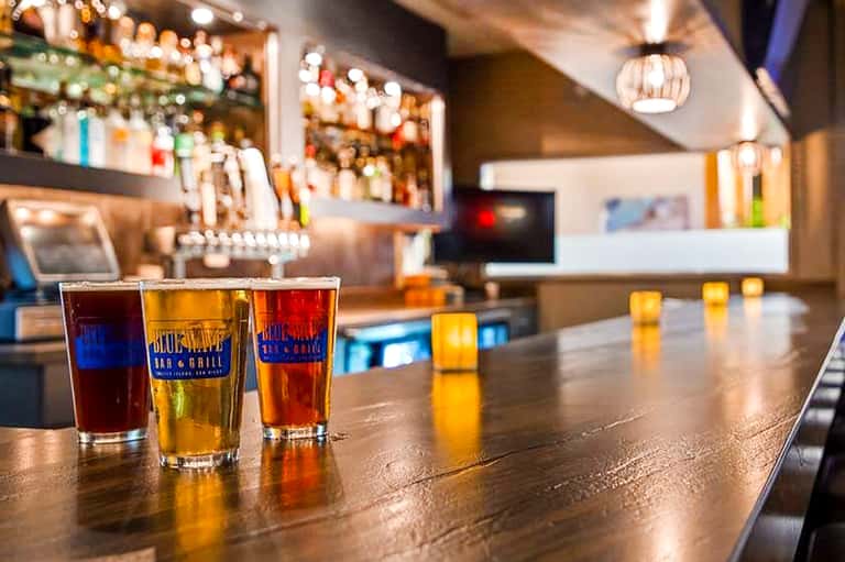 Hotel bar counter with colorful beverages in glasses and stocked shelves with bottles