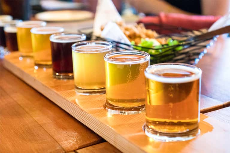 Beer flight tasting board with multiple craft beer glasses on wooden surface