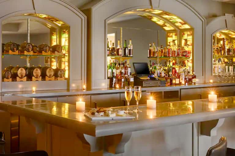 Upscale bar with illuminated glass display cabinets, bottles, and elegant counter seating