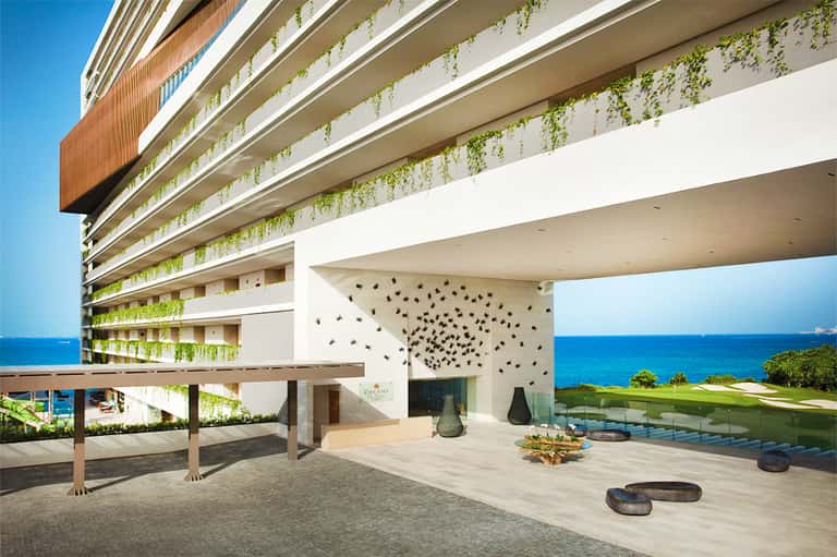 Luxury oceanfront resort with green hanging plants and ocean views from elevated terrace