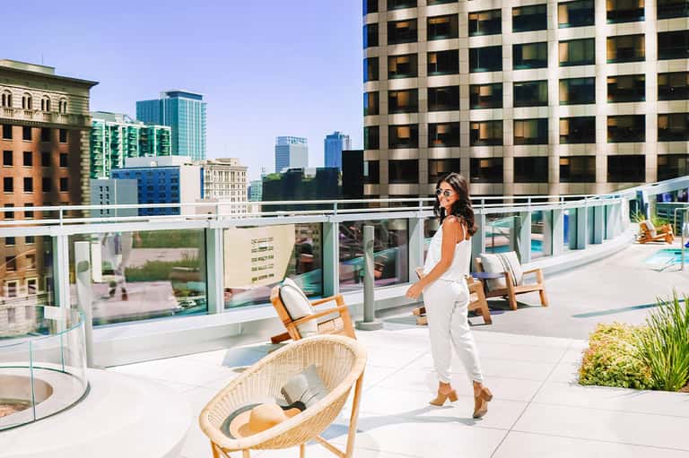 Woman on modern rooftop terrace with city skyline views and contemporary lounge chairs