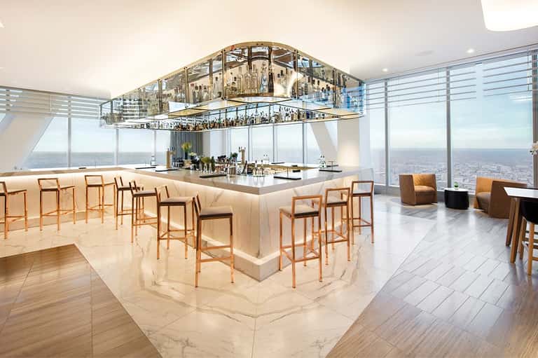 Upscale bar with marble counters, wooden seating, and panoramic ocean or waterfront windows