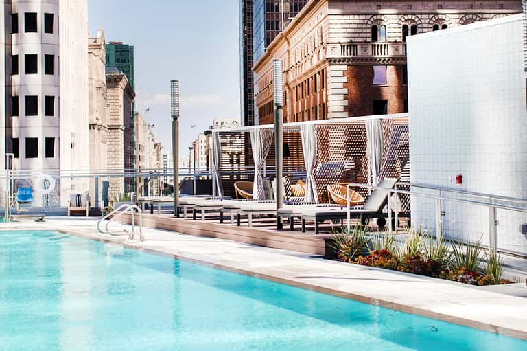 Urban rooftop pool with turquoise water, cabanas, and historic architecture backdrop