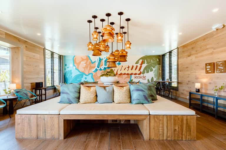 Modern beach-themed bedroom with teal and gold decor, wooden furniture, and tropical wall mural