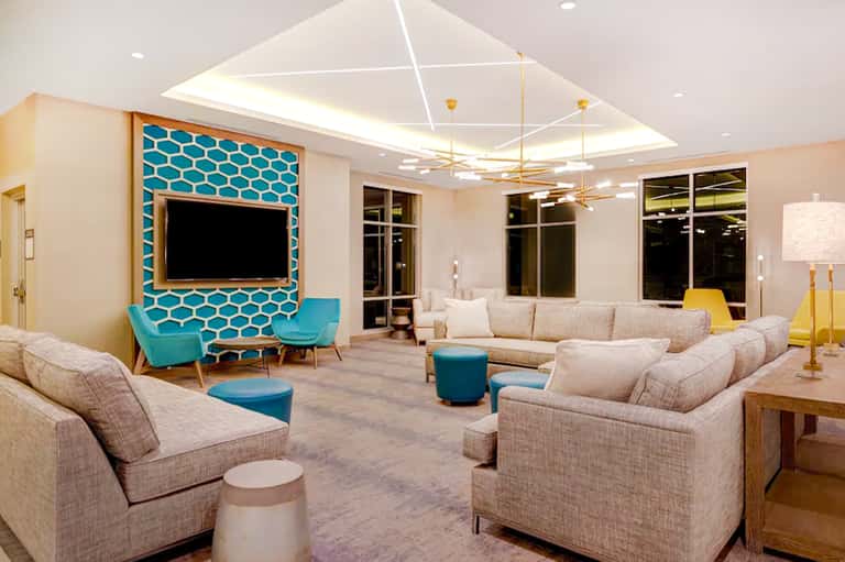 Modern resort lobby lounge with teal accent wall, comfortable seating, and geometric ceiling design