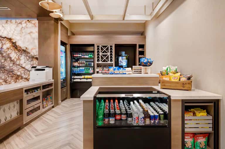 Modern resort snack bar with beverage coolers, vending displays, and wood cabinetry