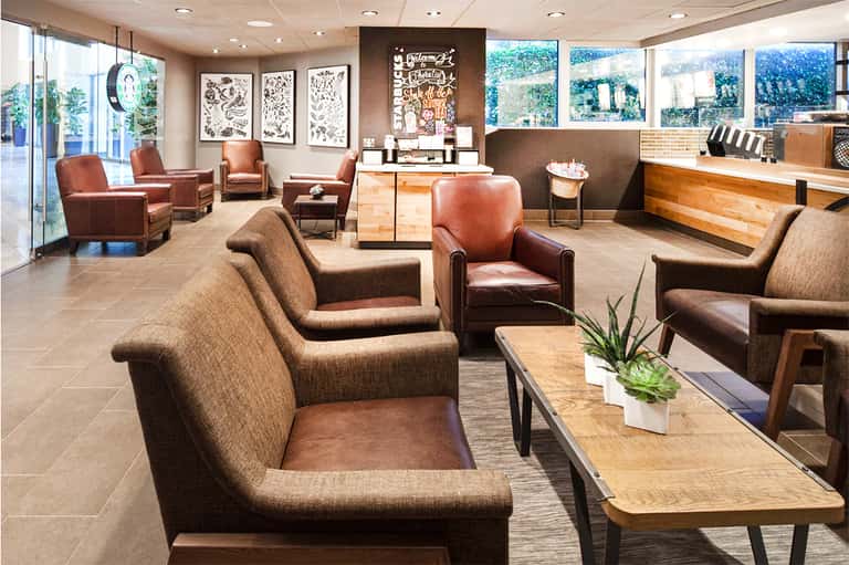 Modern hotel lobby with warm leather seating, wooden accents, and large windows