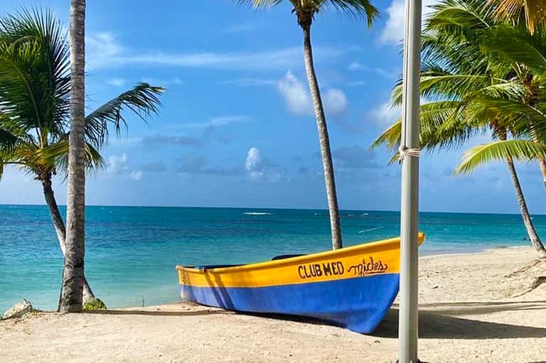 Colorful boat on tropical beach with palm trees and clear turquoise ocean water