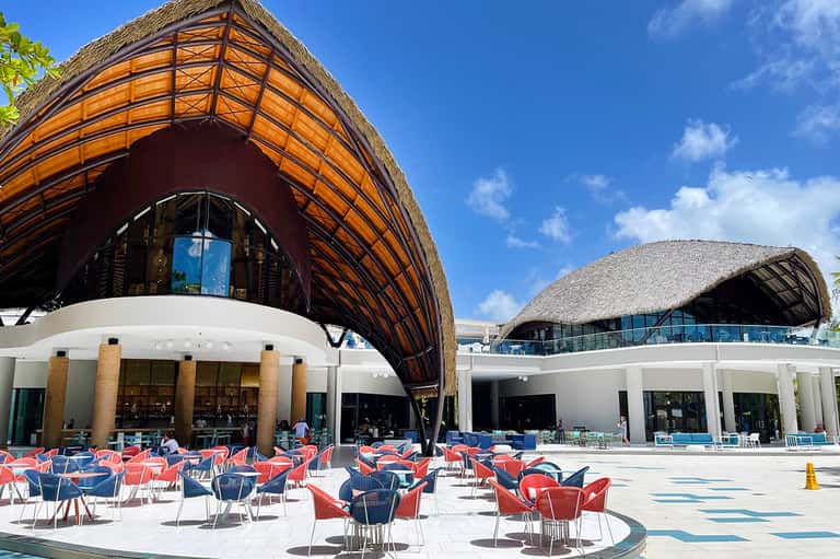 Contemporary resort plaza with thatched-roof structures and red seating areas