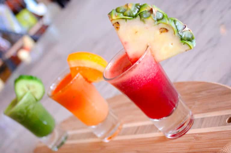 Colorful tropical cocktails with pineapple and citrus garnishes on wooden board