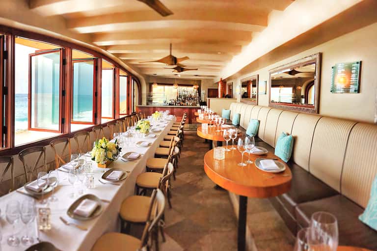 Upscale beachfront dining room with ocean views and elegant table settings