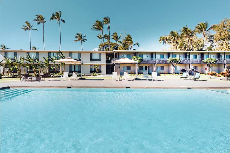 Mid-century modern motel with turquoise pool, palm trees, and retro architecture