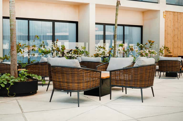 Wicker armchairs with white cushions on modern terrace with ocean views