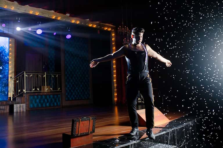Acrobat performing on stage with sparkler effects and theatrical lighting at resort entertainment
