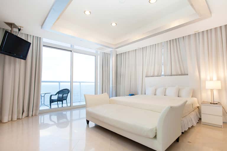 Oceanview bedroom with floor-to-ceiling windows, king bed, and balcony access