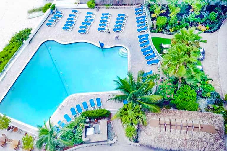 Aerial view of resort pool shaped like bone with lounge chairs and tropical landscaping