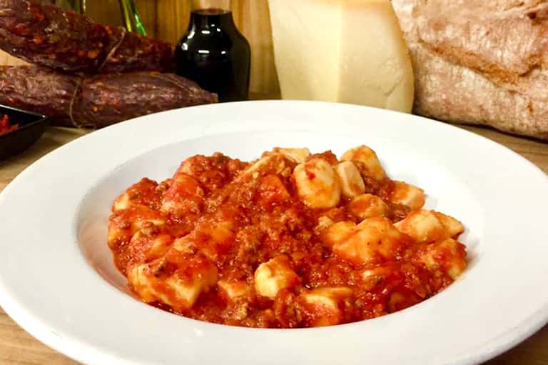 Traditional tomato-based pasta dish with cheese and herbs, served with bread and wine