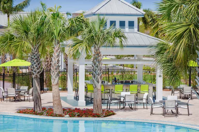Resort pool area with white pergola, palm trees, and lounge seating