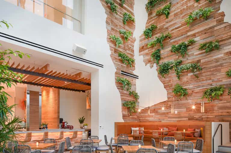 Contemporary resort dining area with living green walls, wooden beams, and modern seating along brick accent wall