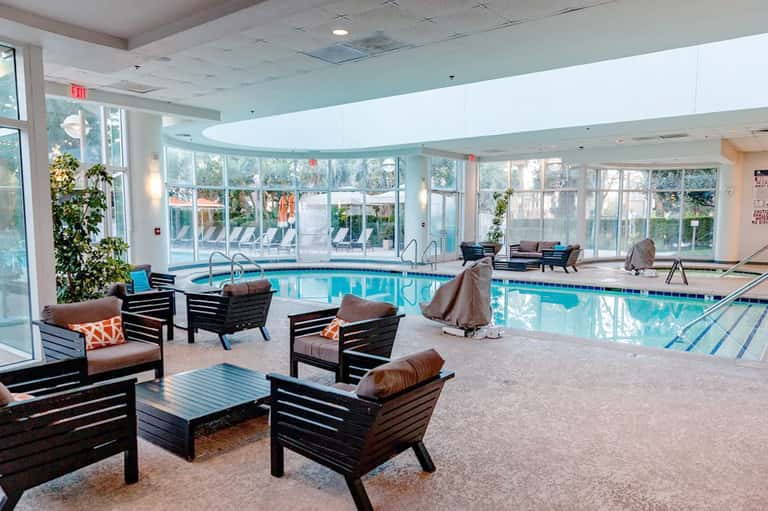 Indoor heated pool with lounge chairs and large windows overlooking grounds