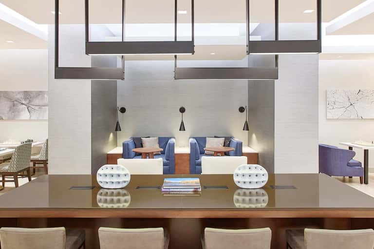 Modern hotel lobby with reception desk, pendant lighting, and contemporary seating areas