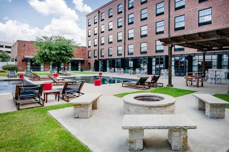 Resort courtyard with fire pits, lounge chairs, and brick building with modern architecture