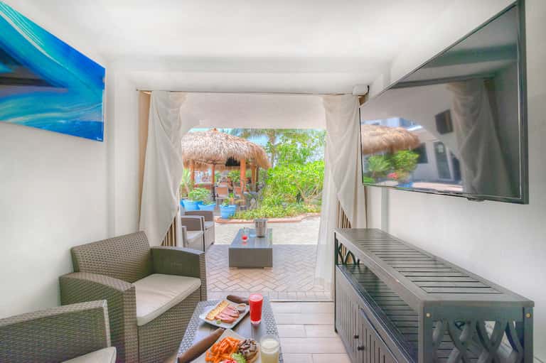 Modern resort suite interior with ocean view terrace, TV, and comfortable seating