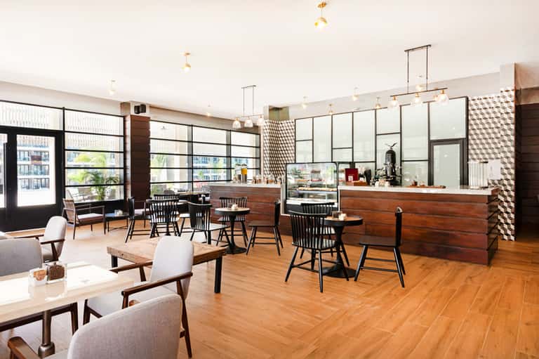 Modern hotel lounge and café with wooden counters, large windows, and mid-century furniture