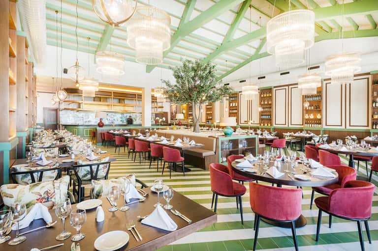 Fine dining restaurant with green striped ceiling, chandeliers, and burgundy chairs