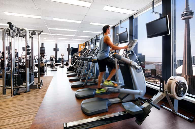 Fitness center with cardio equipment, large windows overlooking city skyline and CN Tower