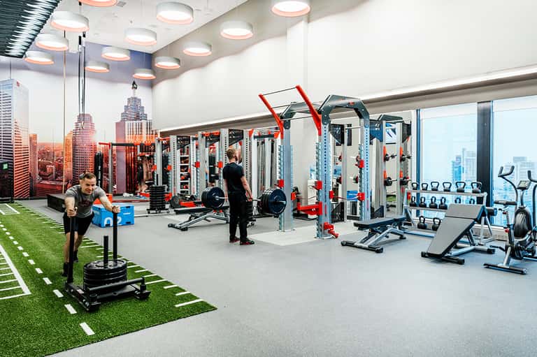 Modern fitness center with gym equipment, mirrors, and artificial turf flooring
