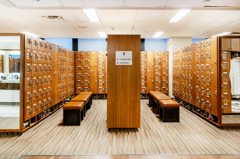 Wooden card catalog drawers covering walls of spa changing room with benches and signage for showers and lockers