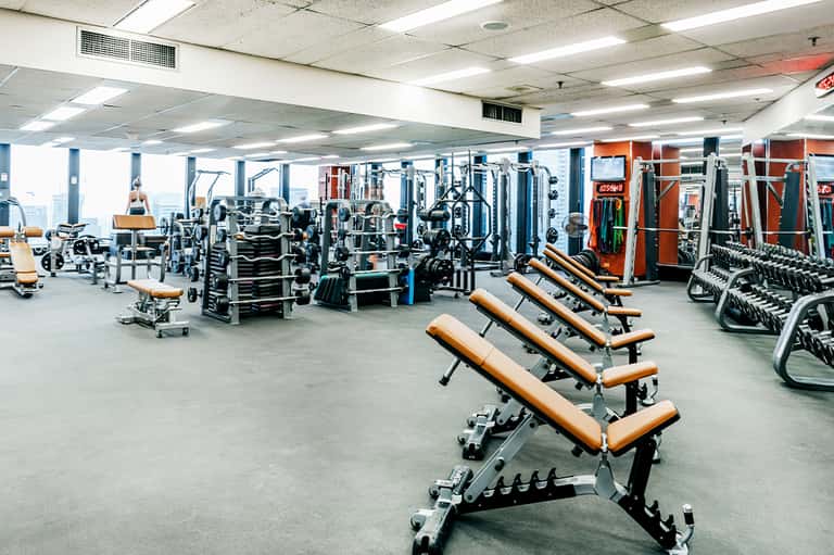 Large gym facility with exercise equipment, weights, benches, and cardio machines