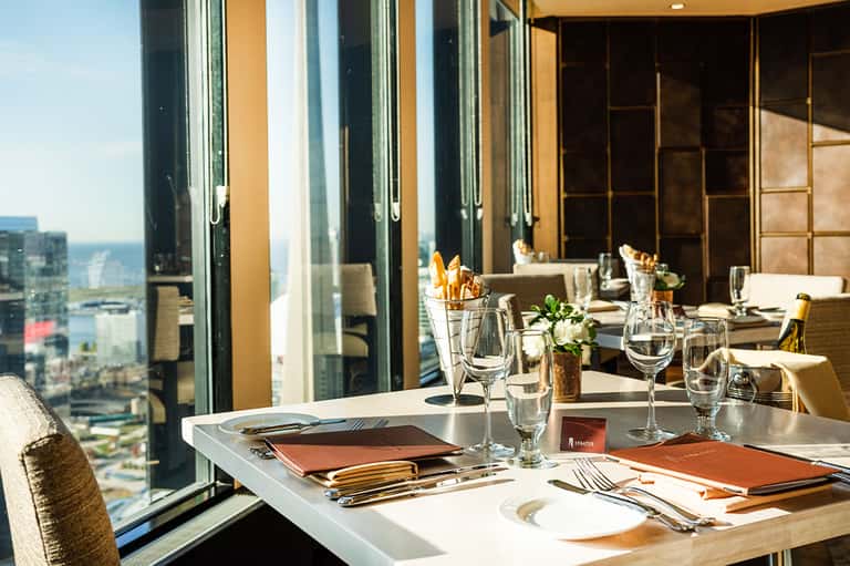 Upscale restaurant dining table with ocean view through floor-to-ceiling windows