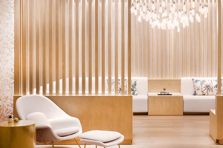 Contemporary spa reception area with wood paneling, white chair, and pendant lighting
