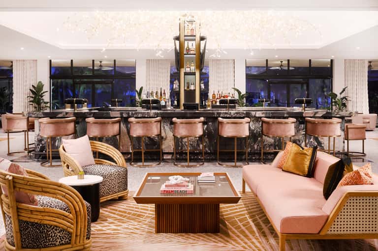 Modern hotel bar lounge with copper barstools, rose-toned seating, and marble accents