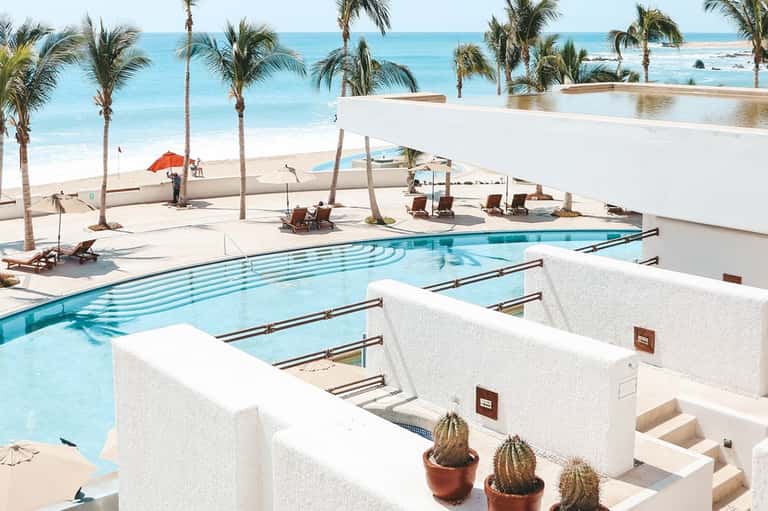 Beachfront pool and spa area with white architecture, palms, and ocean views