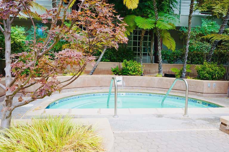 Resort pool with metal railings surrounded by lush green landscaping and tropical plants